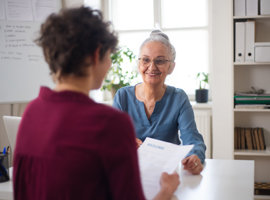 Two women sat at a table looking at paperwork